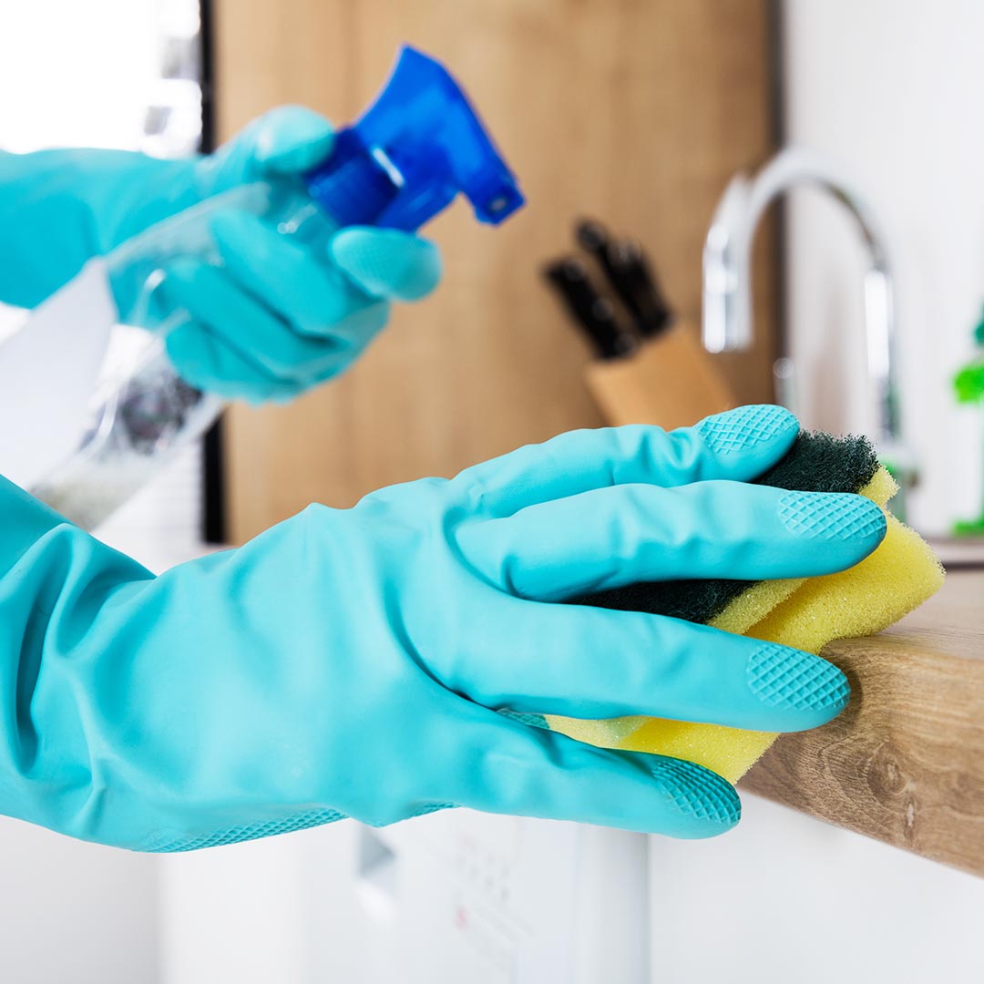 Person wearing blue gloves cleaning a kitchen