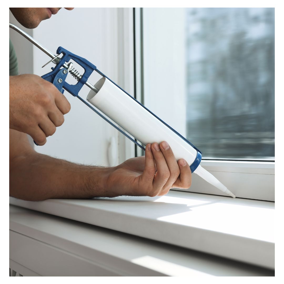 a person sealing a crack by a window